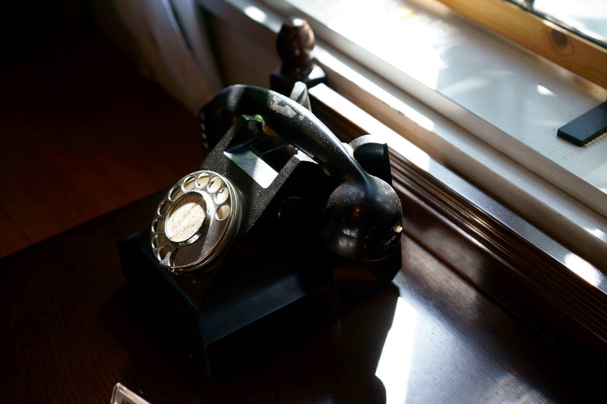 An old rotary phone sitting by a windowsill.