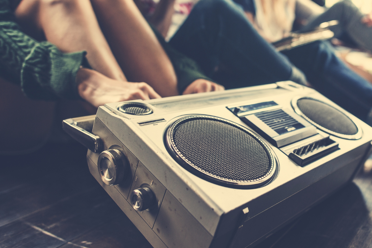 Teens listening to music on a speaker.