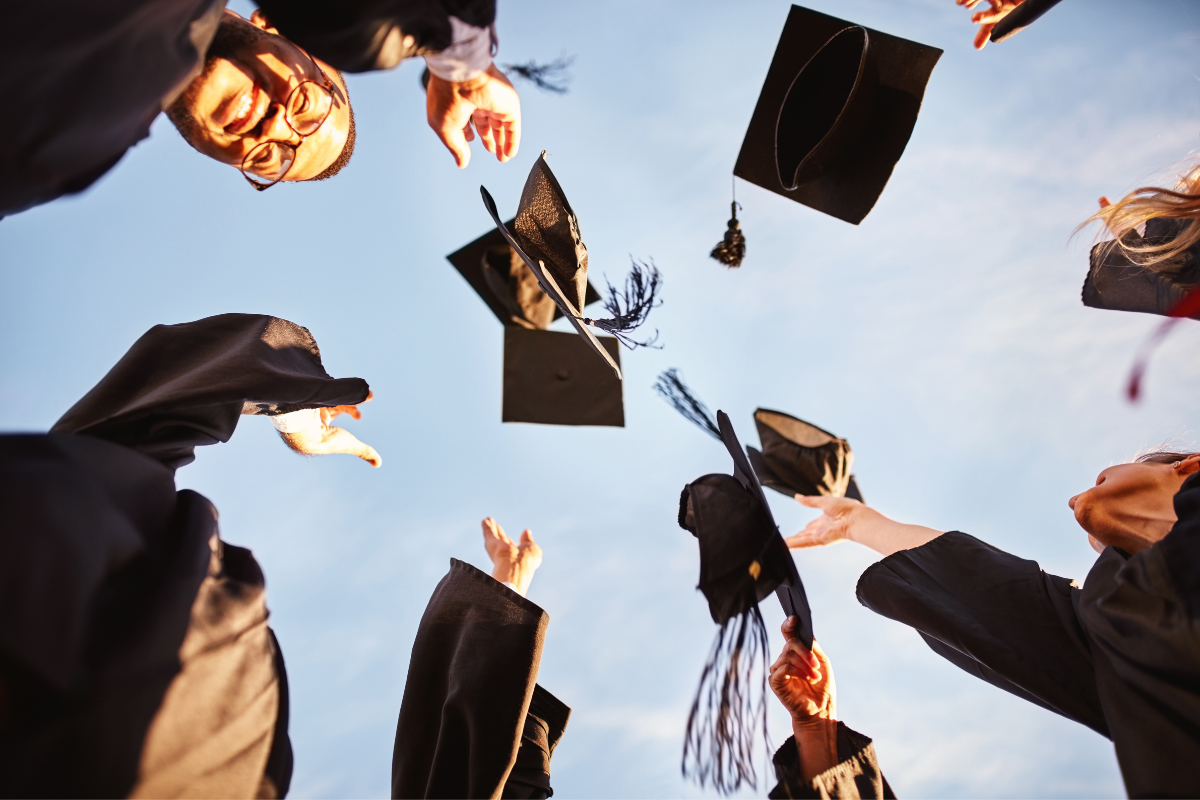 Graduates throwing their caps up into the air.