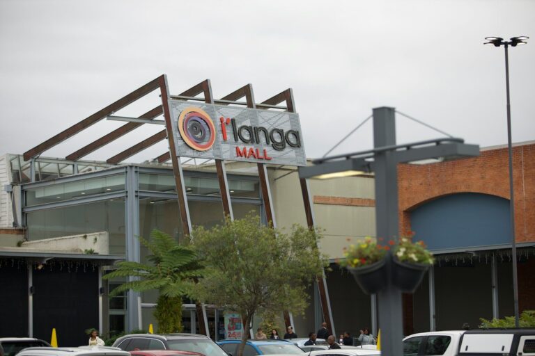 The exterior of i'langa mall with cars and a tree.